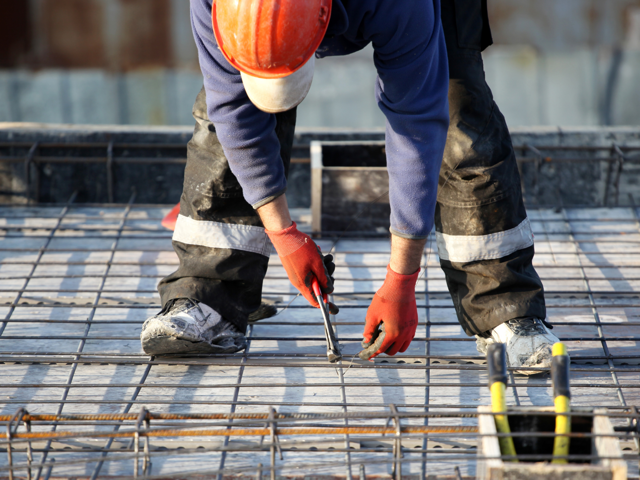 concrete worker aligns re bar for building foundations 